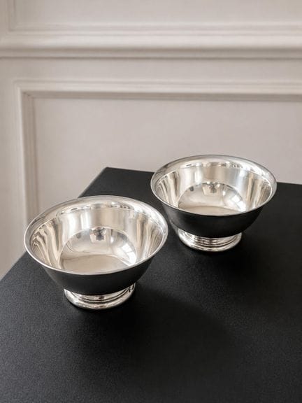 PAR DE COPOS DE METAL PLATEADO
apoyados sobre una 