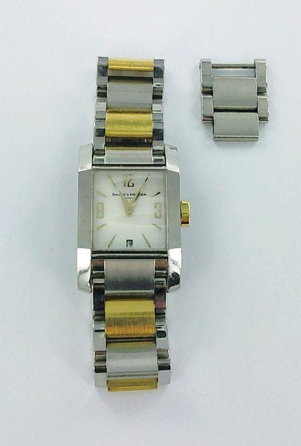 BAUME ET MERCIER。
女士腕表，采用不锈钢与镀金金属材质，表盘为珍珠母贝底，配有折叠表