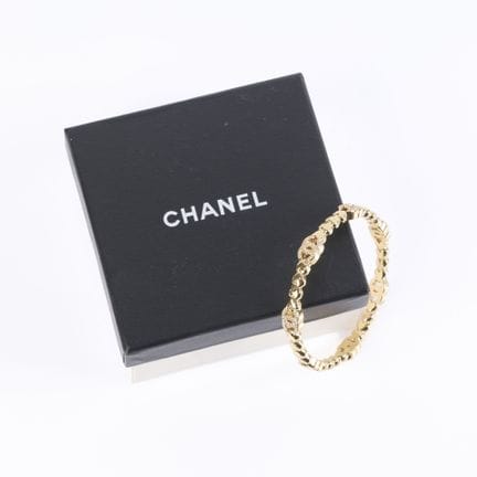 CHANEL. Pulsera tipo esclava de metal dorado con e