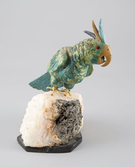 Loro de piedra dura en tonos verdes, posado sobre 