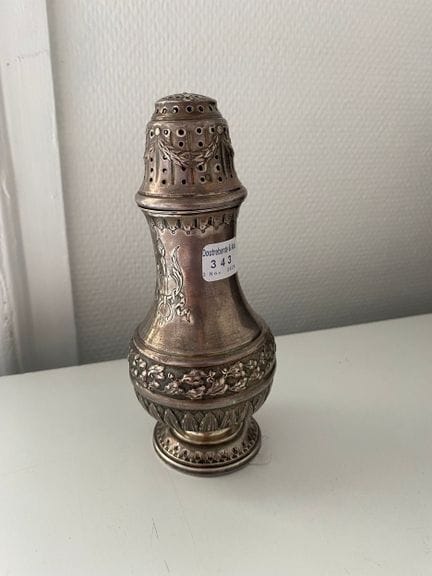 Spolverino in argento 925, poggiante su un piedist