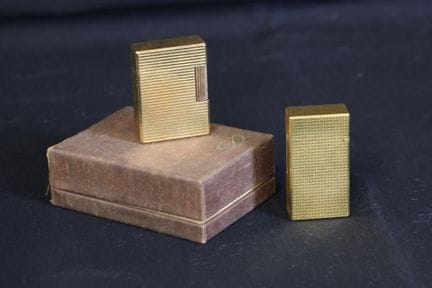 Two gold-colored metal lighters, one of which is a