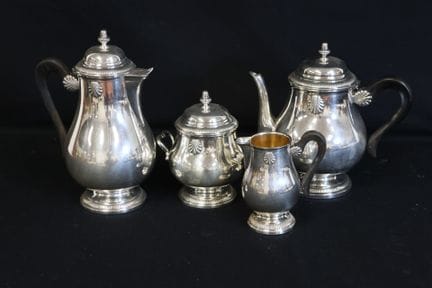 一套镀银的金属茶具和咖啡具，饰有卷纹和贝壳纹样，把手为黑化木质。内壁镀金。