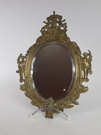Specchio ovale in bronzo con decorazioni a mascaro