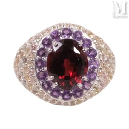 Silver ring featuring a garnet in the center, surr