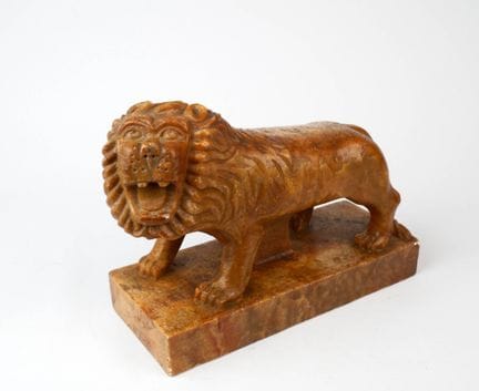 A carved stone lion roaring, resting on a rectangu