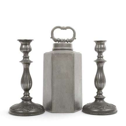 A pewter, angular-sided jug and two pewter candles