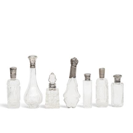 Seven crystal-cut perfume bottles with silver caps