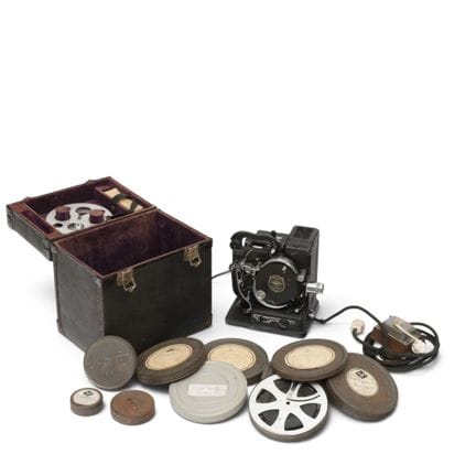 Un proyector de cine y siete películas en cajas me