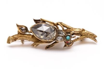 A diamond beetle brooch, perched on a naturalistic