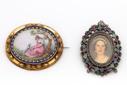一枚 Biedermeier 风格珐琅胸针，以珐琅彩绘出一位女士和她的狗的田园风光。珐琅边饰饰有树叶