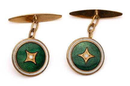 A pair of cufflinks. The round top features green 