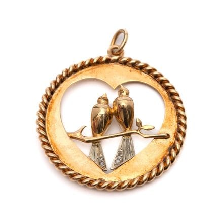 Un pendentif en forme de cœur orné de colombes. Le
