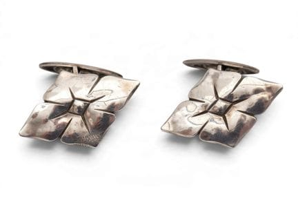 A pair of silver cufflinks in a stylized diamond-s
