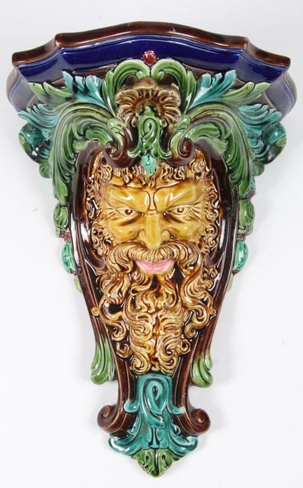 萨雷格米纳斯。大型壁挂式壁炉架，采用多色釉陶制成。饰有萨蒂尔头部图案，周围环绕植物纹样。
背面标有“