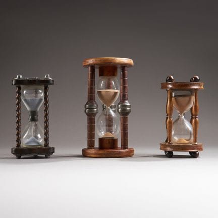 Three glass hourglasses with turned wooden frames 