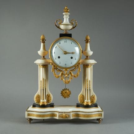 A white marble pendulum clock with chiseled and gi