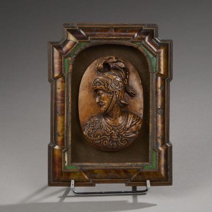 Wooden medallion carved in bas-relief depicting th