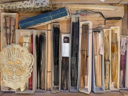 A collection of fans, fan parts, boxes, and fan ri