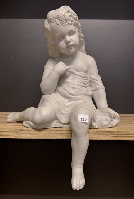Large bisque sculpture of a seated, draped young g