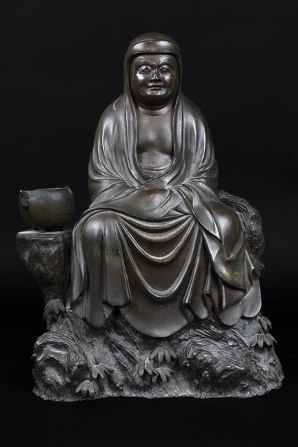 日本，20世纪初 
一尊坐于岩石上的达摩圆雕，其右侧放置着一个香炉。
青铜材质，表面呈褐色包浆，局部