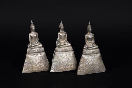 泰国，20世纪。三尊佛像端坐于高高的基座上，呈“指地印”姿势。木芯上覆银箔。高：约15.5厘米。