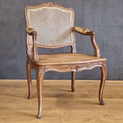 Louis XV-era cane armchair with a flat, ornate bac