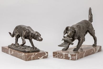two sculptures in bronze depicting a dog, one sign