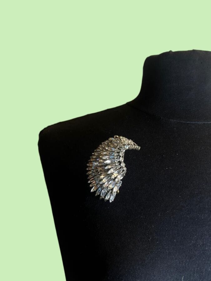 CHRISTIAN DIOR Haute Couture by ROGER JEAN PIERRE Brooch clip: Wing-shaped, made of white gold-patinated metal with navette- and round-cut rhinestones—unsigned 
Height: 7 cm