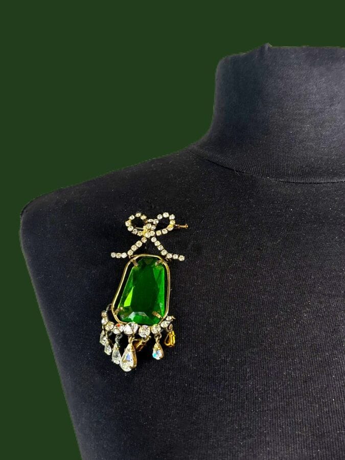 Attributed to DIOR Jewelry brooch with a patterned design and pendants in silver-patinated metal, cut green glass, and rhinestones—unsigned
Height: 8.5 cm
