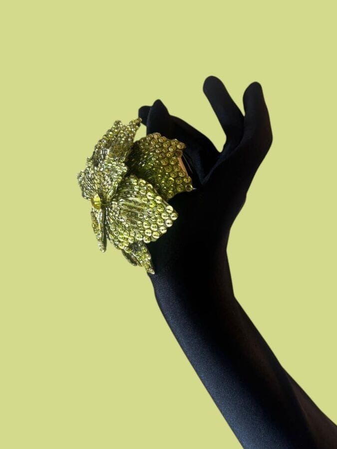 LESAGE Black Bakelite cuff bracelet with a fabric flower embellished with sequins and green rhinestones—unsigned 
Inner diameter: 5 cm
Motif: 9x8 cm
(Source: Lesage boutique liquidation sale)
