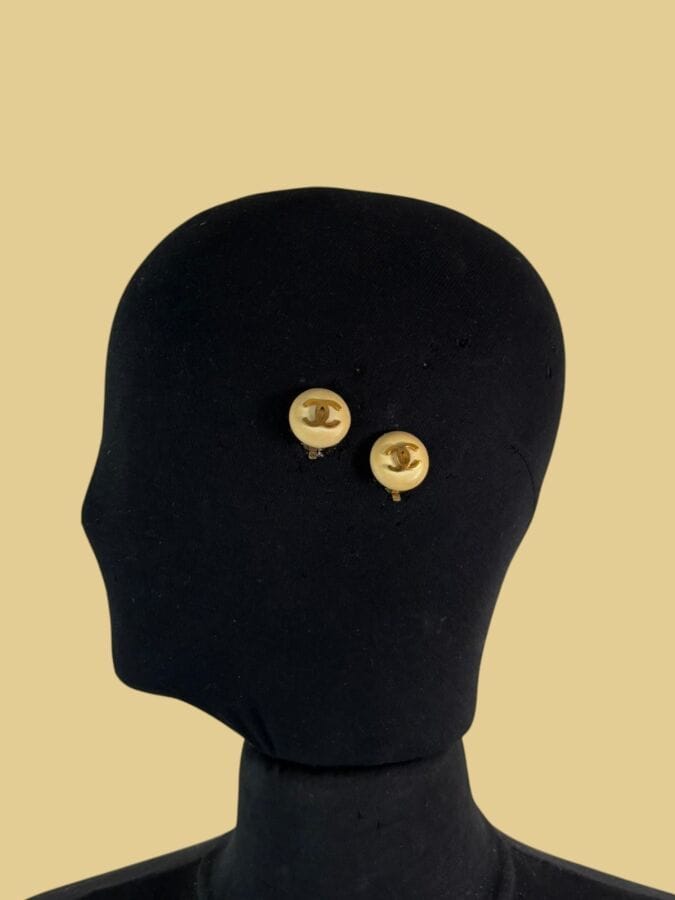CHANEL Made in France  Paire de clips d'oreilles en bakélite ivoire et sigle métal doré - signée
Diam 2 cm
(salissures)