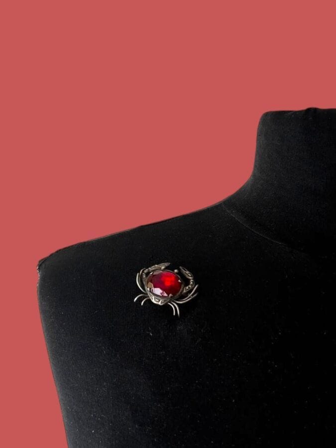 PAUL WIEGANT Broche crabe en métal argenté et verre facetté rouge - non signée                                                                                                                     3,3x2,3 cm