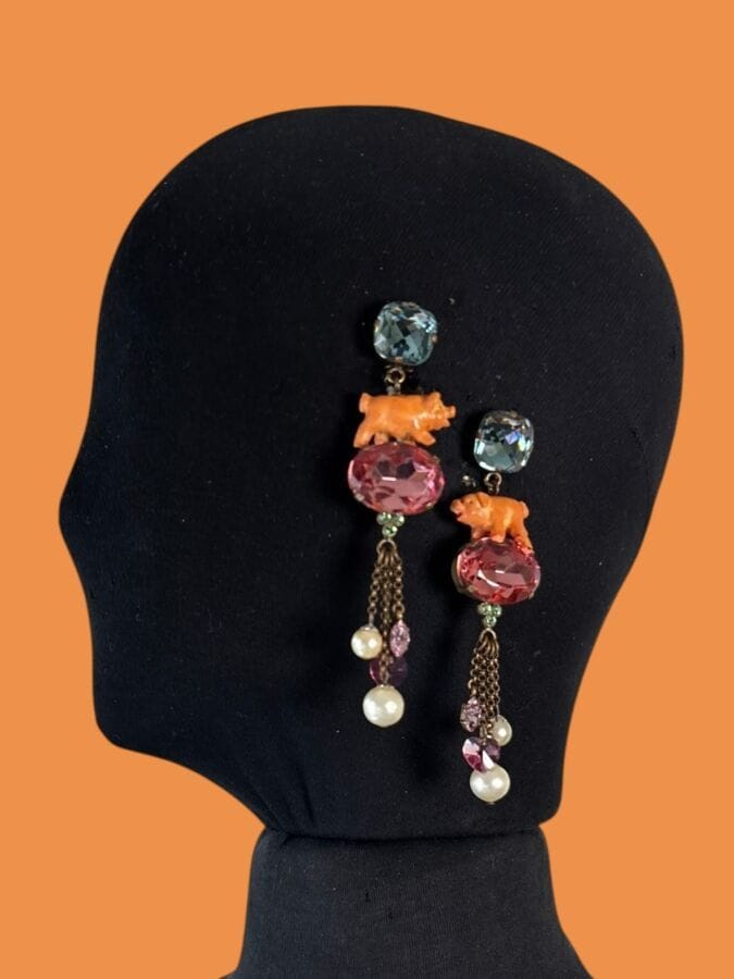 ROSA TEMPLIN Pair of dangling ear clips with a patinated metal frame, a small resin pig, pink and blue rhinestones, and pearlescent beads—signed
Height: 10 cm
