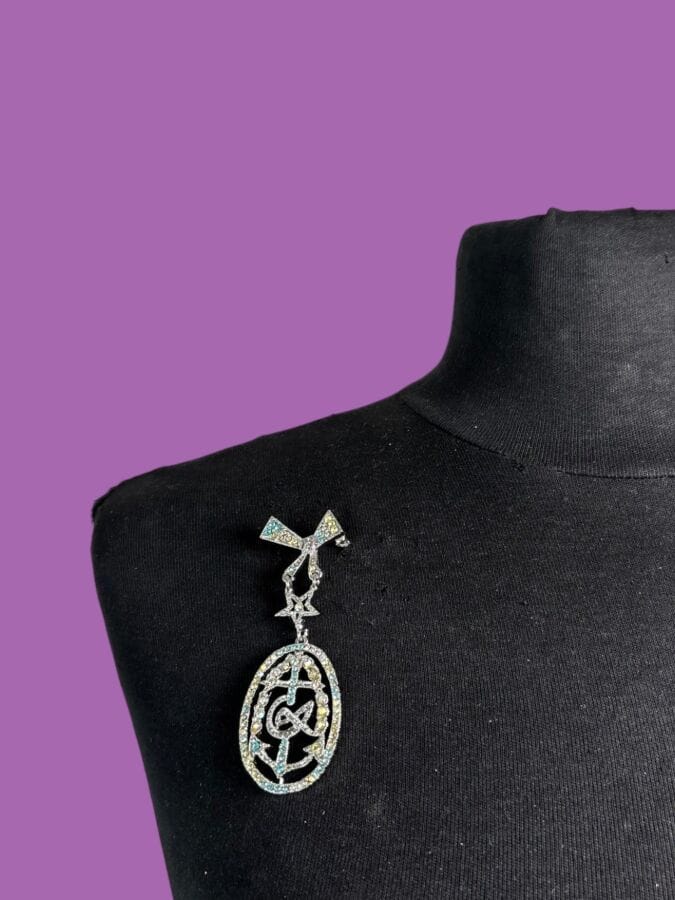 CHRISTIAN LACROIX Broche à médaillon croix camarguaise en métal patine argent et strass aurore boréale au chiffre de la marque 
Ht 7,5 cm