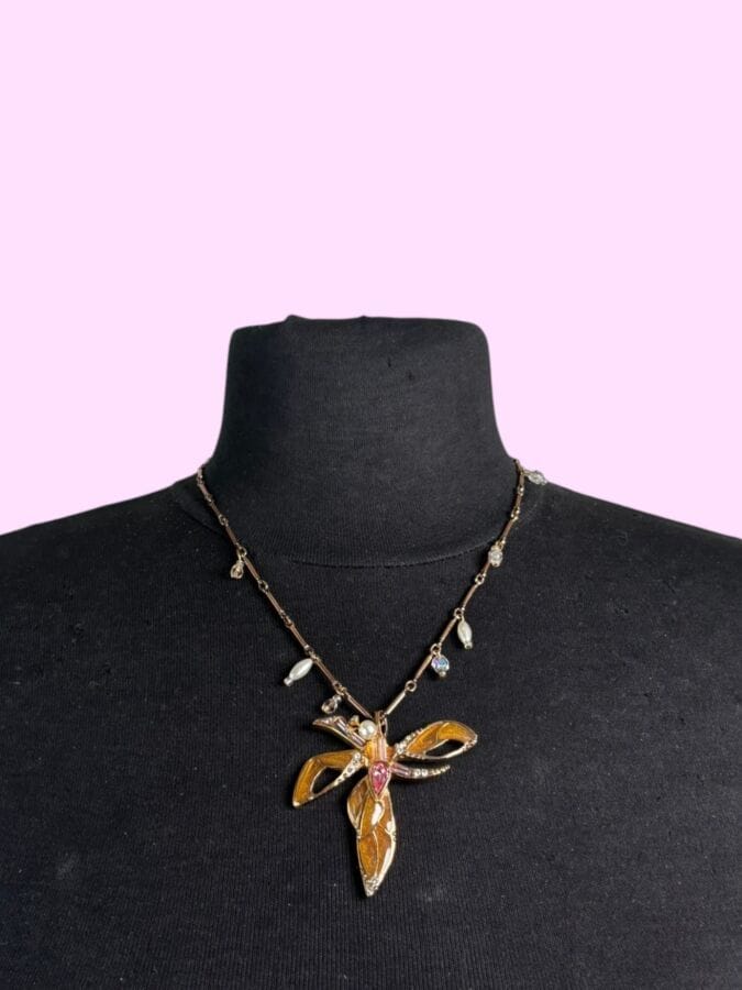 CHRISTIAN LACROIX Made in France  Necklace with a stylized dragonfly pendant in gold-plated metal with cream enamel, pink and white rhinestones, and a pearlescent pearl—signed, with a pouch 
Height: 28 cm
