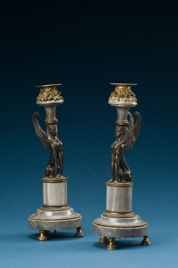 Pair of patinated and gilded bronze candlesticks, with a gray marble base and bowl; the shaft is decorated with a sphinx, Empire style. 
Height: 26 cm.