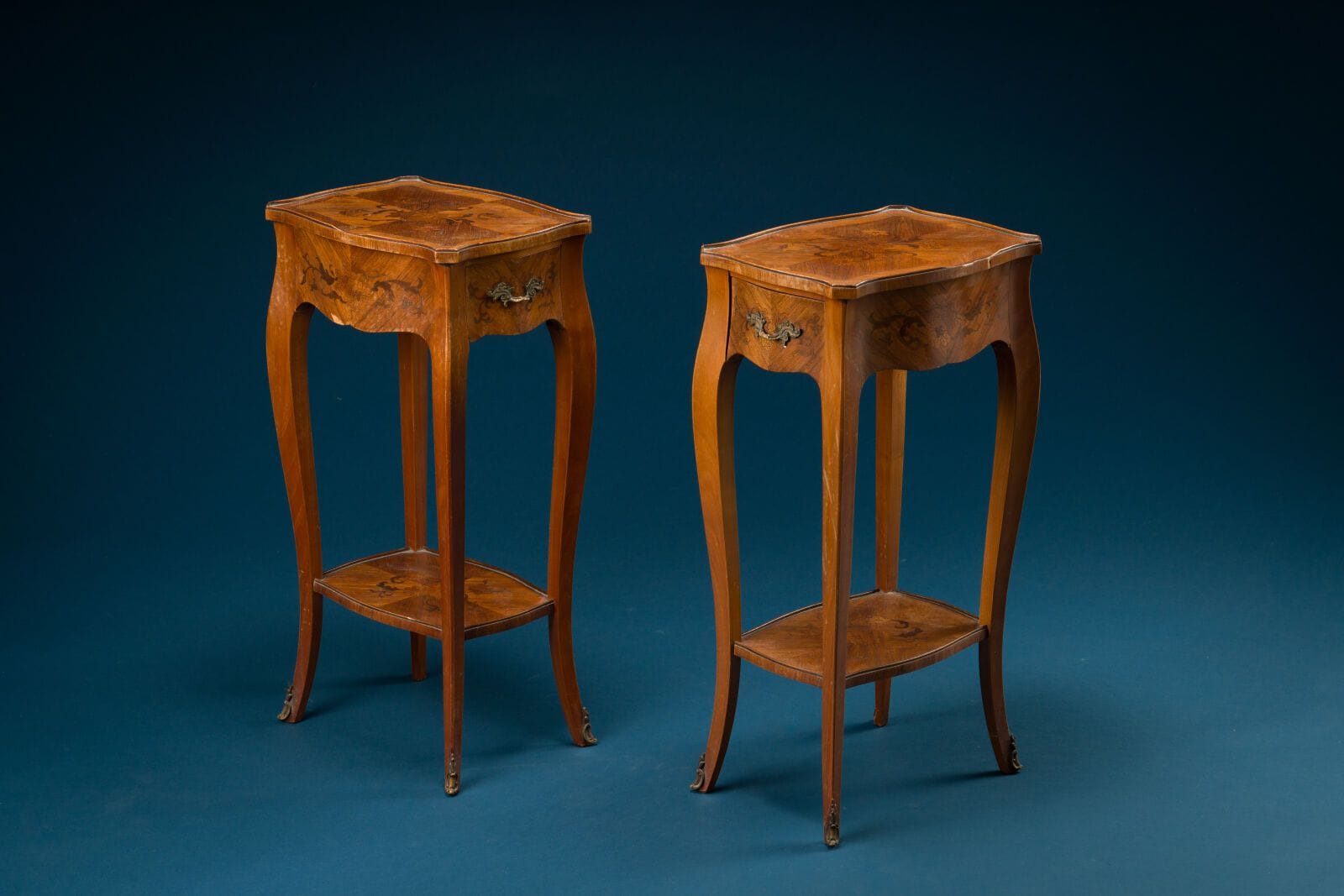 Two small side tables made of veneered wood with floral decoration, featuring a drawer and a shelf
Louis XV style
H.: 68 cm; W.: 36 cm; D.: 25 cm. 
(One leg is damaged, and there are a few small chips in the veneer)