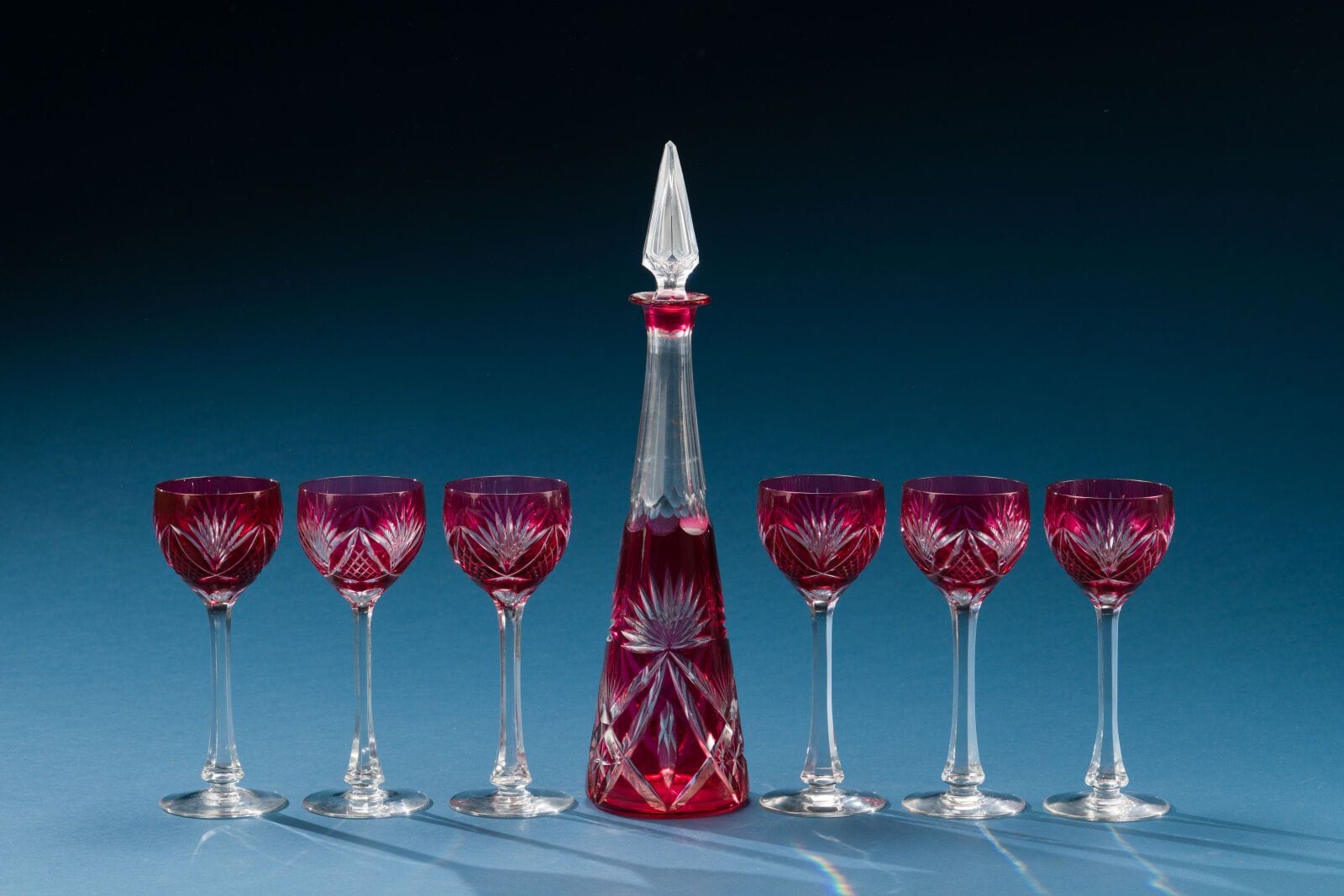 A set of six Rhine wine glasses and a red-bottomed cut crystal decanter.
Height (of the decanter): 42 cm.