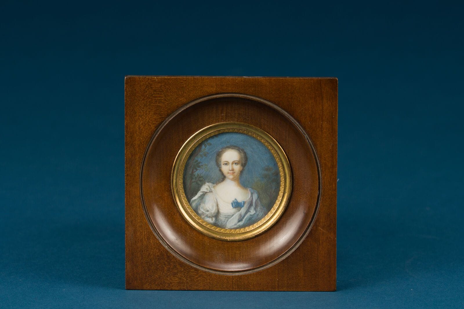 French School, in the 18th-century style
"Portrait of a Woman, Blue Background" 
Round miniature
Inscription on the back: Wife of Nicolas Jullien (1685–1753), mother of Pierre Nicolas Jullien des Bordes (1728–1795), and grandmother of Jean Baptiste Pierre Jullien, Chevalier de Courcelles
Diameter: 4.5 cm.
