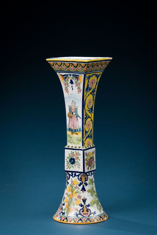 QUIMPER
A long-necked, quadrangular earthenware vase decorated with flowers and thistles. 
Signed "HB QUIMPER" on the base. 
Height: 46 cm.
