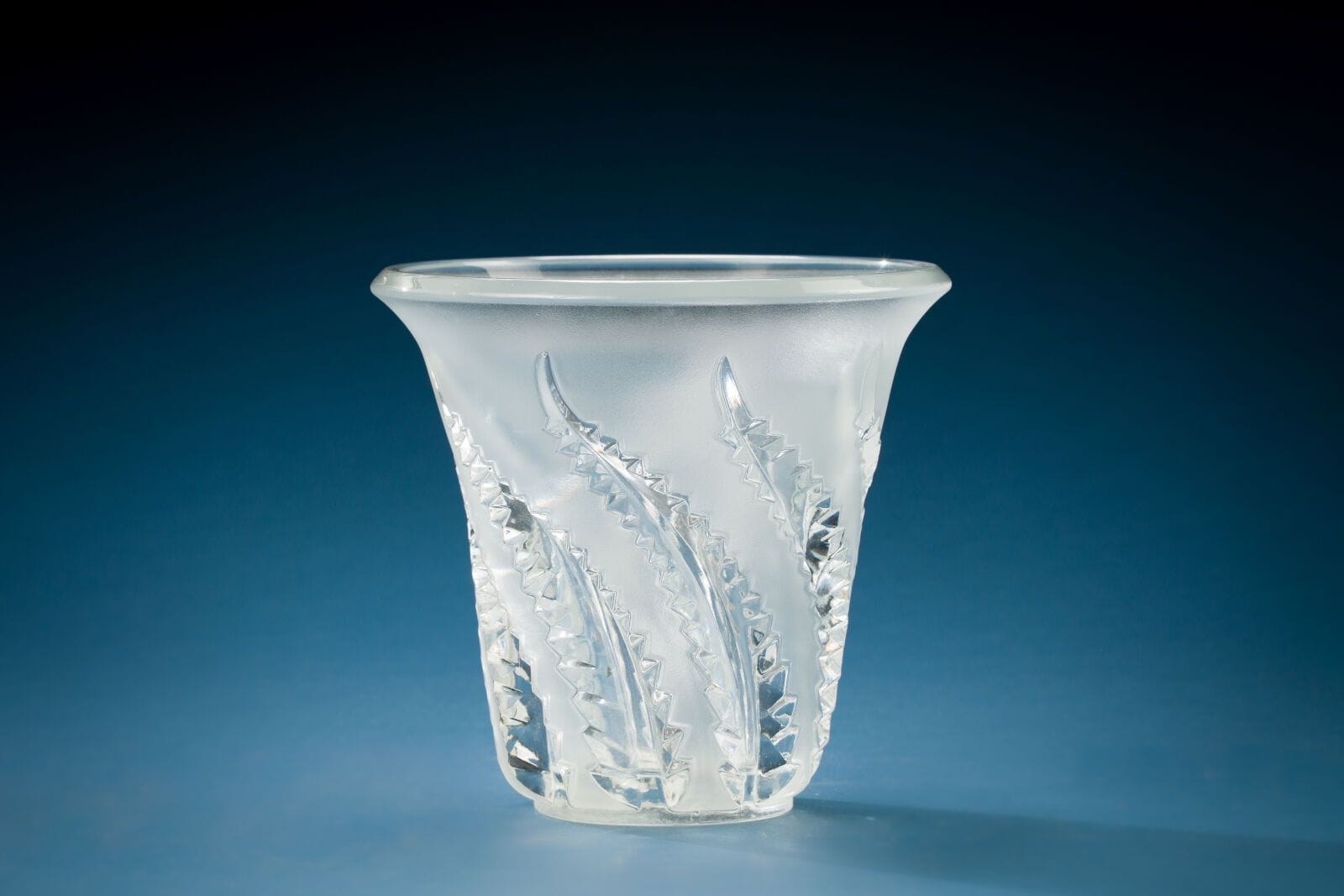 LALIQUE FRANCE
White and opalescent crystal tulip vase, decorated with engraved leaves. 
Height: 19.5 cm; Diameter: 20 cm. 
(slight chip on the base)