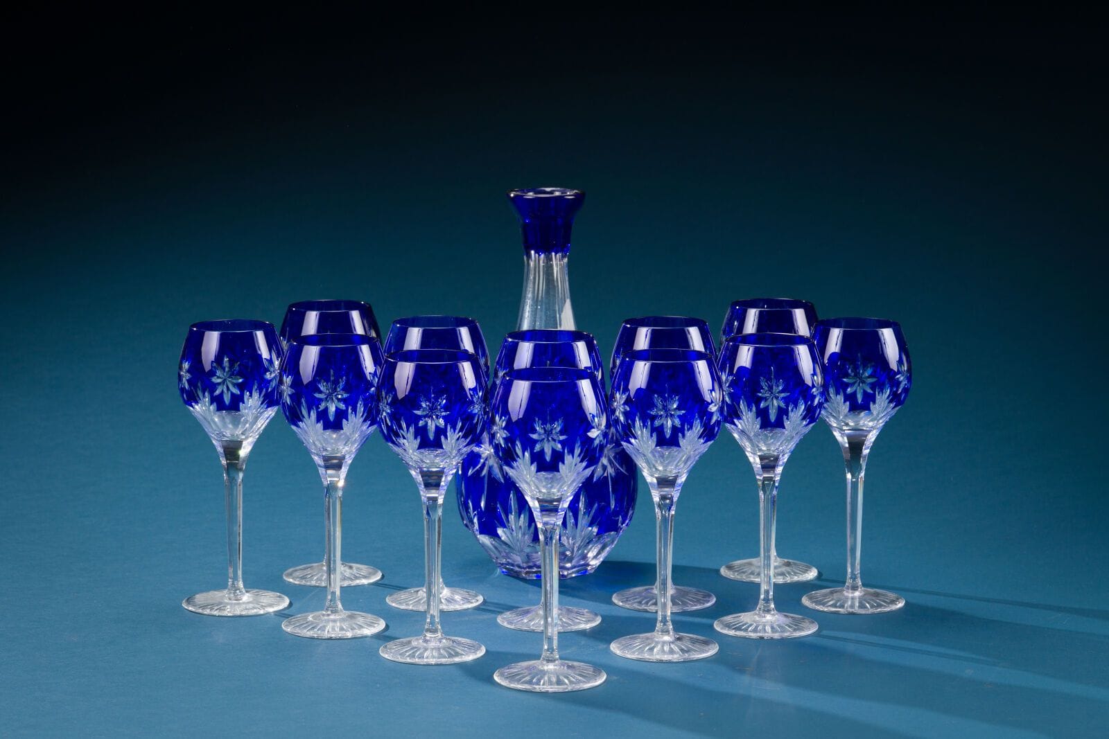 A set of twelve Rhine-style stemmed glasses and a cut crystal decanter with a blue base. 
Decanter height: 31 cm. 
(Decanter stopper missing).