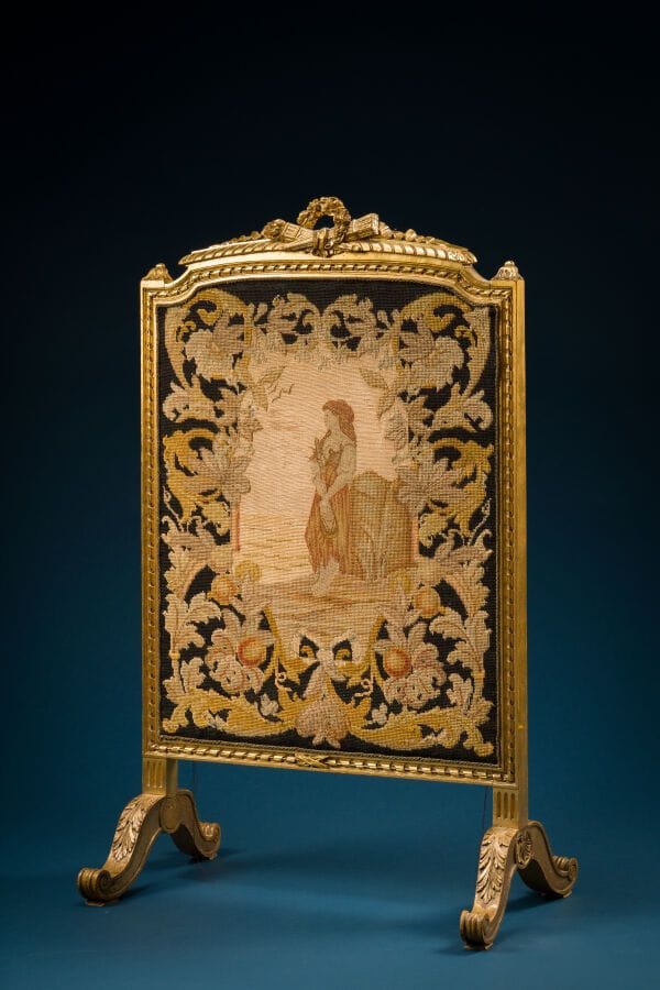 Gilded wooden screen decorated with symbols of love
Louis XVI style, circa 1900.
A panel embroidered with a female musician in a medallion 
Height: 110 cm; Length: 67 cm.