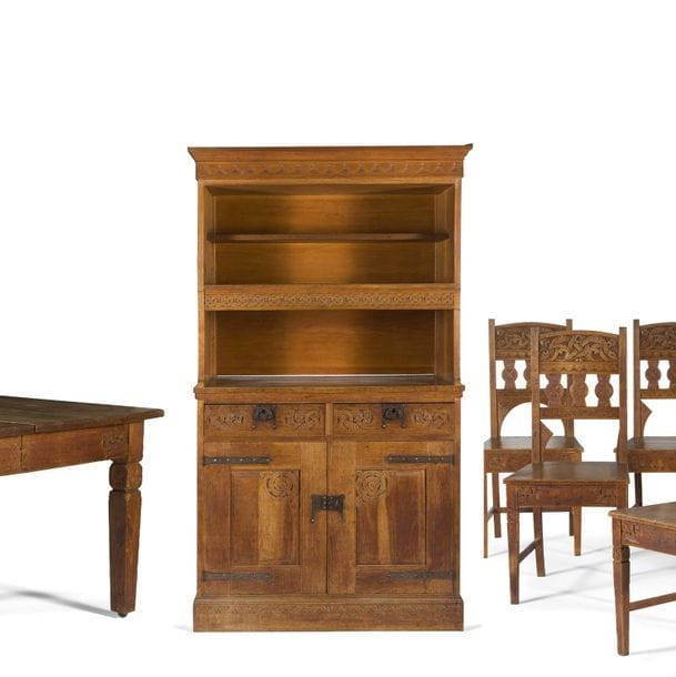 ART NOUVEAU NORVÉGIEN - DRAGESTIL - STYLE NÉO-VIKING 
Mythologies scandinaves  
Important ensemble de salle à manger en chêne réalisé vers 1905 et composé comme suit : 
- Un meuble deux-corps formant vaisselier. La partie basse reposant sur plinthe et ouvrant, en façade, par deux portes et deux tiroirs. La partie haute présentant des étagères formant niches et une tablette. Les vantaux, les façades de tiroir, la plinthe et la corniche au décor de motifs sculptés. Pentures, entrées de serrure et prises articulées en fer forgé et ouvragé. État d'usage, accidents et manques. H. 216 cm - L. 119 cm - P. 50 cm 
- Un meuble de boiserie ouvrant par une porte en façade et reposant sur plinthe. Le vantail, les montants latéraux, la corniche et la plinthe au décor de motifs sculptés. Entrée de serrure et prise articulée en fer forgé et ouvragé. Partie latérale gauche sans plinthe et sans corniche. H. 152 cm - L. 86 cm - P. 33 cm 
- Une table rectangulaire pouvant recevoir des alonges (non fournies). La ceinture large et en retrait présentant sur chacune de ses faces des motifs sculptés. Les quatre pieds d'angle et les deux pieds centraux de soutien de type gaine. État d'usage. H. 73 cm - L. 126 cm - P. 110 cm  
- Une suite de 7 chaises. Les hauts dossiers, en partie barreaudés, aux motifs sculptés. Les ceintures larges présentant sur chacune de leur face des motifs sculptés. Les pieds en gaine et réunis par des entretoises en H. Manquent des parties d'arcatures sur certains dossiers, des barres d'entretoise sur certaines chaises, état et restaurations d'usage. H. 94 cm 
On y joint, faisant suite au mobilier précédent, réalisée à l'époque par un atelier parisien : 
Une console à un plateau d'entrejambe. La ceinture large et en retrait présentant sur chacune de ses faces des motifs sculptés. Les pieds de type gaine présentant un dé sculpté. H. 102 cm- L. 110 cm - P. 49 cm