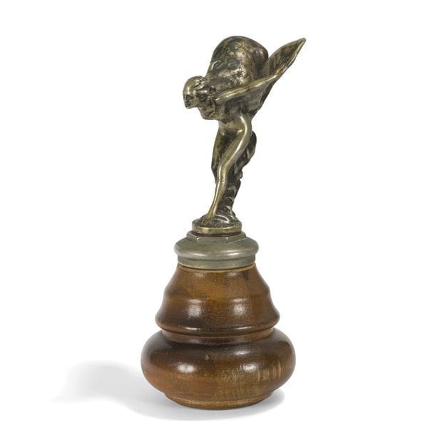 CHARLES ROBINSON SYKES (1875-1950)  
Spirit of ecstasy, le modèle créé en [1911], exemplaire n°34/250 
Mascotte Rolls-Royce formant bouchon de radiateur. Épreuve en métal argenté. Montée postérieurement sur un socle en bois. Marquée ROLLS ROYCE CHARLES, porte une date [191 ?], justifiée 34/250 sur le pourtour de la base et porte l'inscription Trade Mark Reg à l'intérieur de l'aile gauche et Reg.U.S.Pat.Off à l'intérieur de l'aile droite. H. sujet seul : 13 cm - H. avec socle : 25 cm