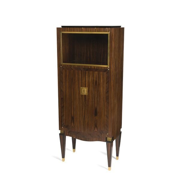 MAISON DOMINIQUE - ANDRÉ DOMIN (1883-1962) & MARCEL GENEVRIÈRE (1885-1967) 
Très élégant cabinet formant meuble vitrine en placage de marqueterie d'ébène de macassar. La façade ouvrant par deux portes surmontées d'une niche munie d'une porte vitrée à l'encadrement en laiton. Les pieds de type gaine, à facettes en ressaut, sabotés de bronze doré et surmontés d'un chapiteau également en bronze doré. Plaque de serrure en bronze doré. Intérieur, équipé d'étagères et de tiroirs, réalisé en bois clair et en chêne. Circa 1945. État et restaurations d'usage. H. 151 cm - L. 62 cm - P. 35 cm 
 
Provenance : 
- Vente Me Sadde Dijon, 19 octobre 2008, lot 189. 
- Collection M. X., Rambouillet. Œuvre acquise lors de la précédente. 
 
Bibliographie : 
Mobilier et Décoration - Août, septembre, octobre 1945. Notre meuble provient d'un ensemble (vente citée en référence) qui comportait une enfilade dont le modèle est reproduit page 13. Notre cabinet présente les mêmes caractéristiques esthétiques et techniques que cette enfilade dont il formait la suite.
