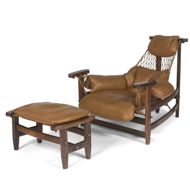 JEAN GILLON (1919-2007) DESIGNER & WOODART ÉDITEUR 
Rare et intéressant fauteuil de repos et son ottoman en jacaranda. Suspentes des assises et du dossier constituées de filets. Coussins des assises, du dossier et des accotoirs en cuir brun d'origine. Étiquette d'éditeur sous une des traverses du fauteuil. Fauteuil : 83 x 89 x 106 cm - Ottoman : 38 x 66 x 44 cm