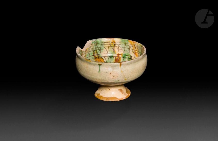 Coupe calice en céramique à motifs géométriques, Chypre, XIIe-XIIIe siècle 
Céramique argileuse à panse hémisphérique sur piédouche. Décor incisé sur fond crème et glaçuré de deux couleurs vert et brun. Au centre, rondeau à motifs géométriques, frise de pétales et sur la paroi, lignes hachurées. 
Diamètre : 12,5 cm et 8,5 cm 
État : pied restauré et manque au rebord. 

A pottery cup, Cyprus, 12th - 13th century
