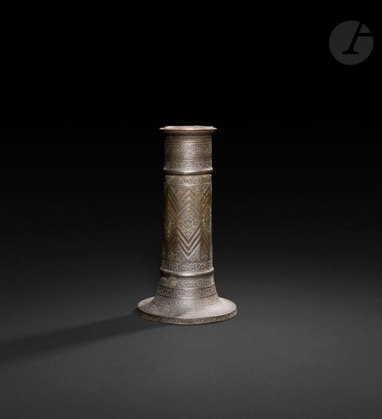 Flambeau, masha’l, en bronze, Iran, XVIIIe - XIXe siècle 
Fût cylindrique légèrement à pans coupés à rainures en chevrons alternés de fleurons. En partie haute, trois frises à inscriptions poétiques et nom de possesseur : « Sahib Muhammad Hassan » dans un cartouche et « Abul Hassan » gravé postérieurement. En partie basse, trois frises de rinceaux floraux. 
Hauteur : 29 cm 

A candlestick, mash’al, Iran, 18th - 19th century